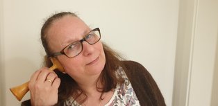 Projektmitarbeiterin mit Brille hält ein Pinardsches Herztonhörrohr an ihr Ohr